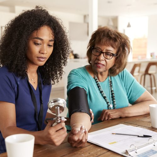 Female healthcare worker checking the blood pressure of a senior woman during a home visit Female healthcare worker checking the blood pressure of a senior woman during a home visit